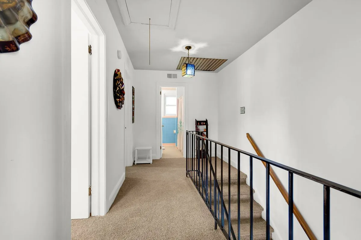 A bright hallway showcases a decorative stair railing, wall art, and a stylish light fixture. The scene conveys a sense of welcome and movement, evoking transitions between home and the outside world—a nod to the convenience and access highlighted in the section.