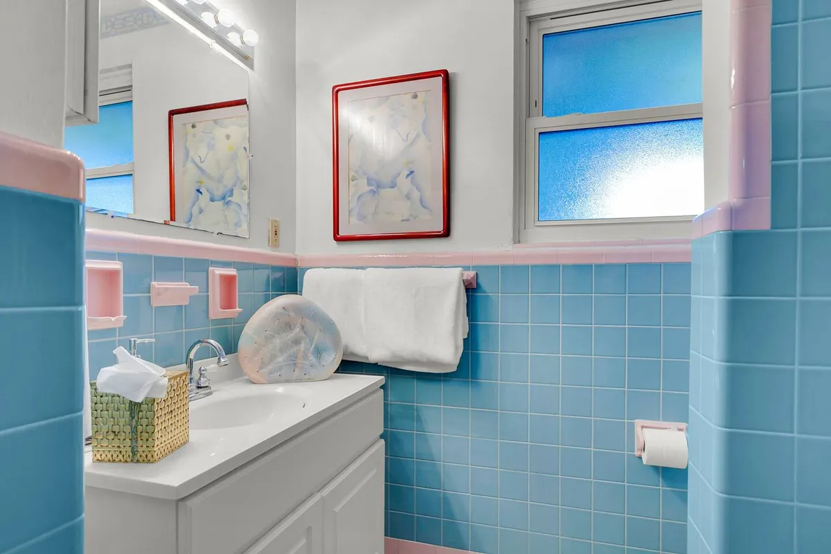 This vibrant image highlights a bathroom with decorative artwork, colorful tiles, a sink, and neatly arranged towels. The cheerful mood and playful details convey a homey atmosphere that enhances the experience of daily grooming and relaxation.